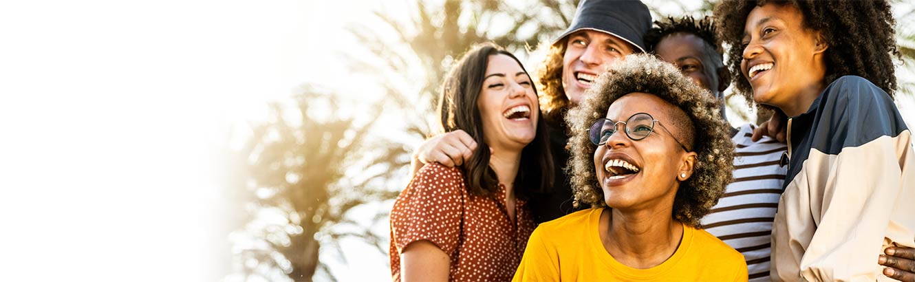 A group of five friends hugging and smiling outdoors.