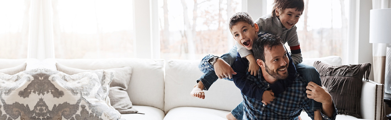 Father and children wrestling on the couch.