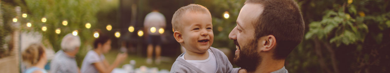 Man holding child outside smiling.